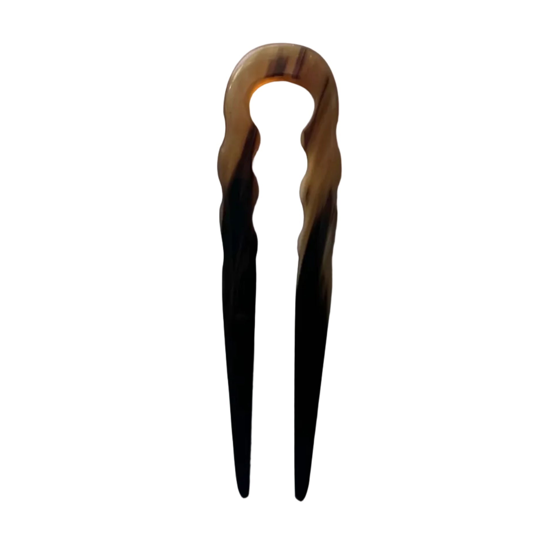 A tortoiseshell hair claw clip with a marbled amber-brown and black pattern, shown against a plain light gray background with soft window light shadows.